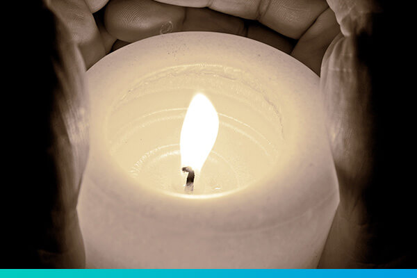 Eine brennende Kerze mit einer Hand